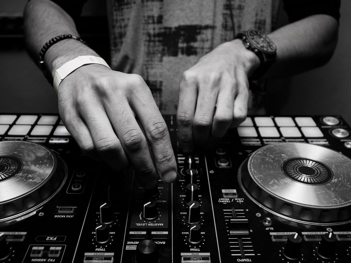 Hands on a DJ mixer and turntable